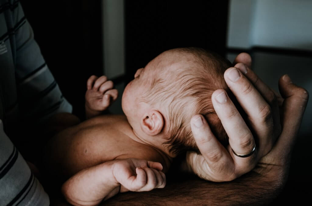 A newborn baby being held by an adult