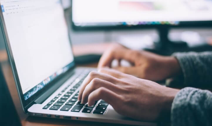 Hands typing on laptop
